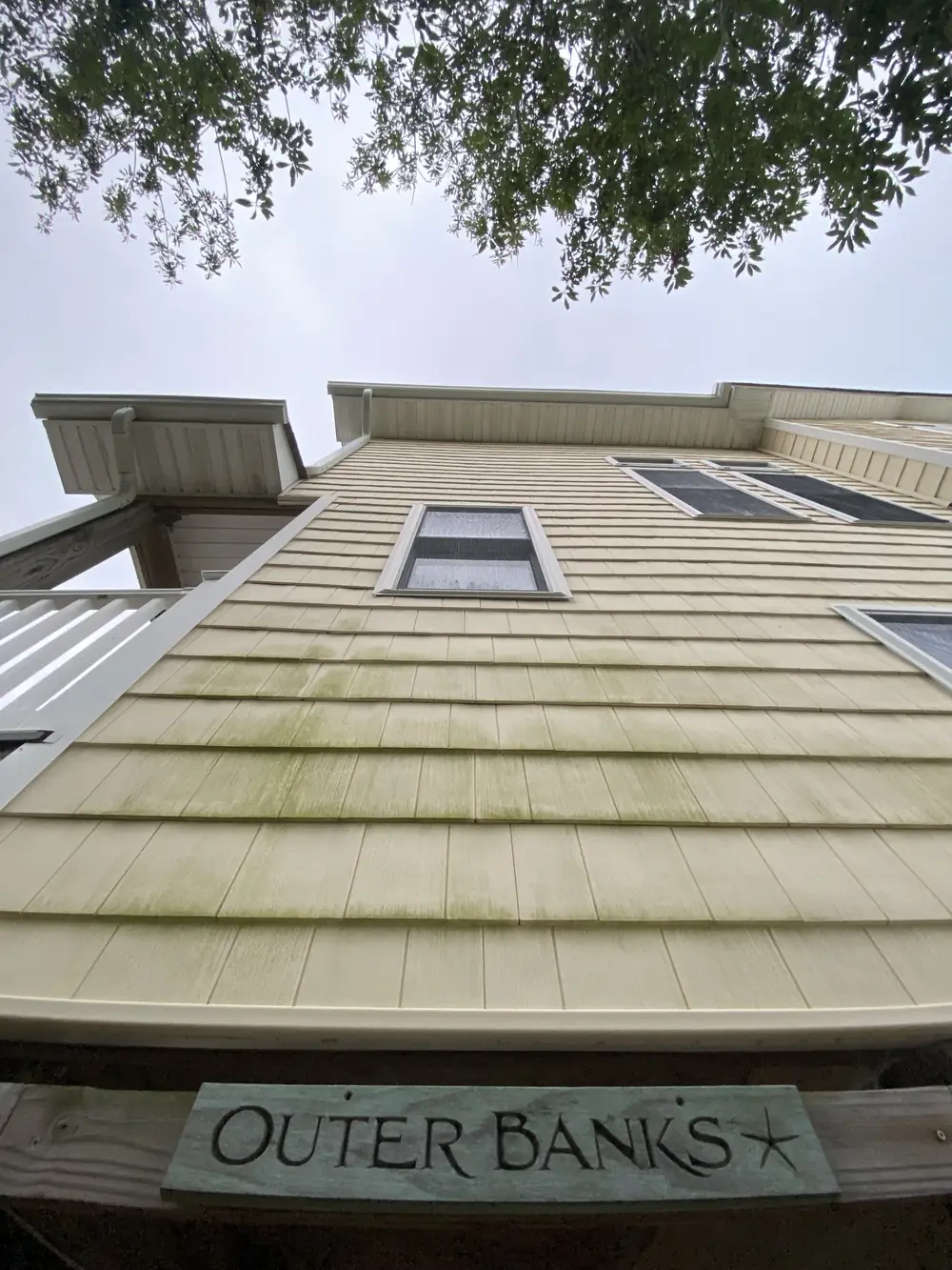 Outer Banks beach house siding streaked with green algae before soft washing