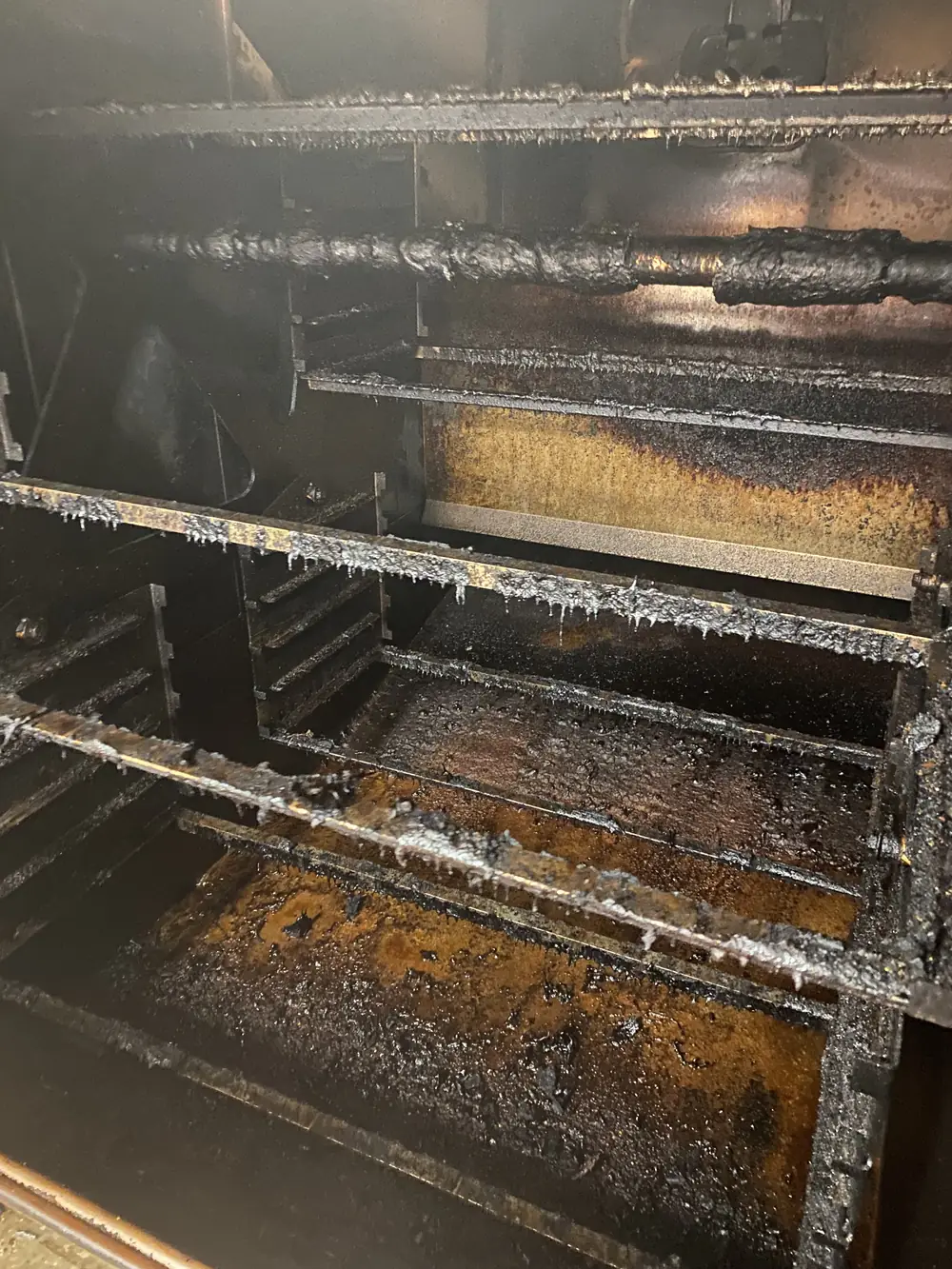 Commercial BBQ smoker interior caked with grease before cleaning
